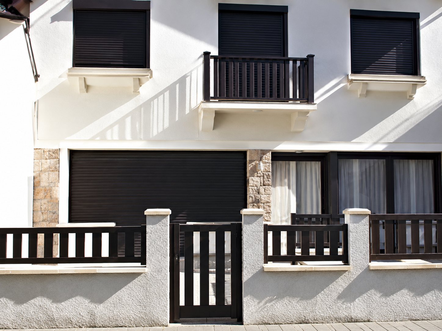 Façade d'un immeuble blanc à plusieurs étages avec des balcons à balustrade et un portail en fer forgé au rez-de-chaussée.