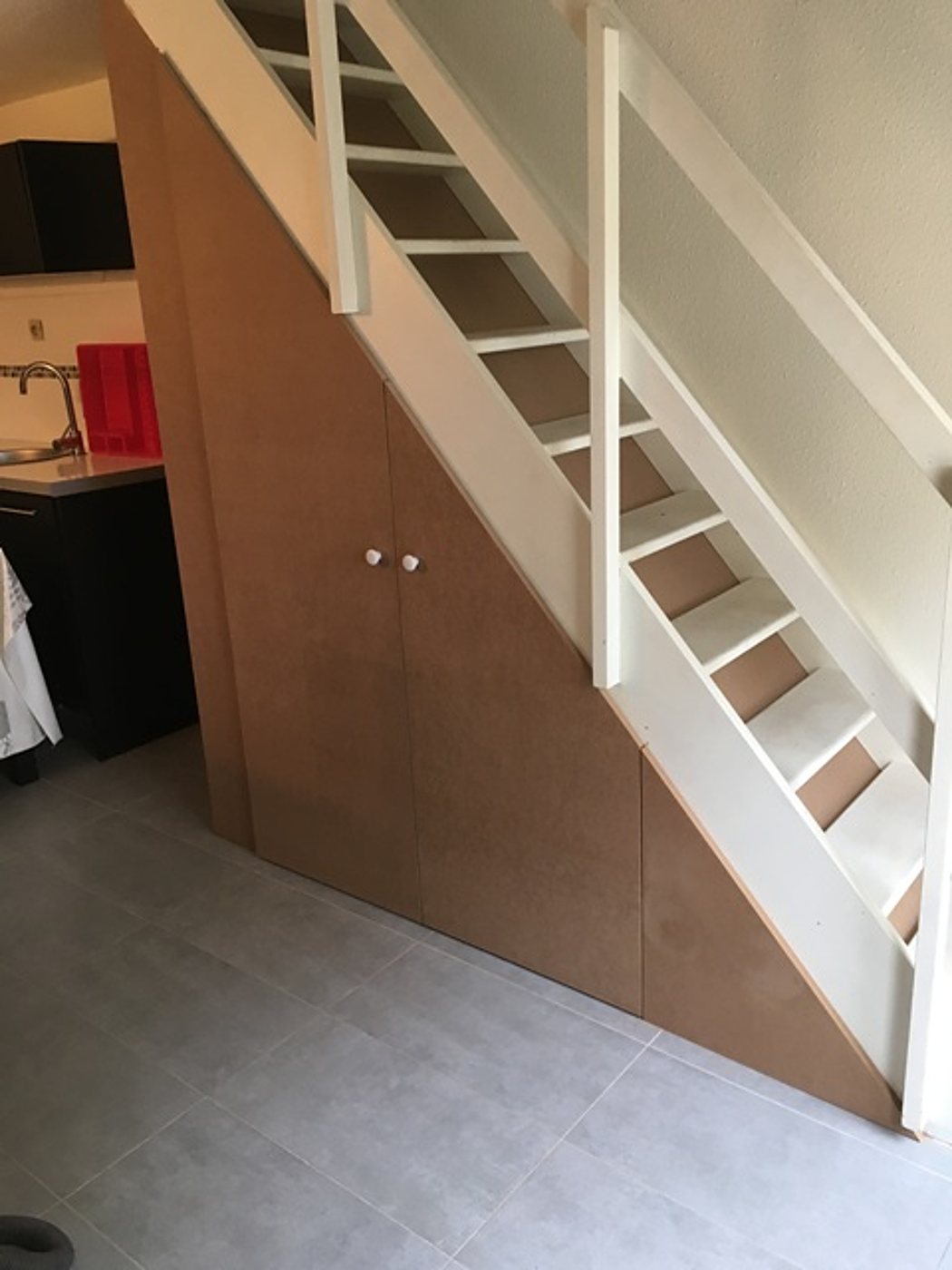 Placard sur mesure en bois sous un escalier blanc
